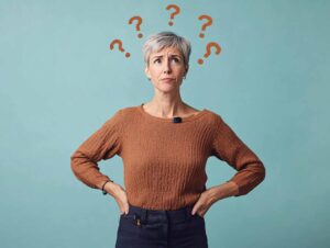 Bild: Eine nachdenkliche Frau mit vielen Fragezeichen